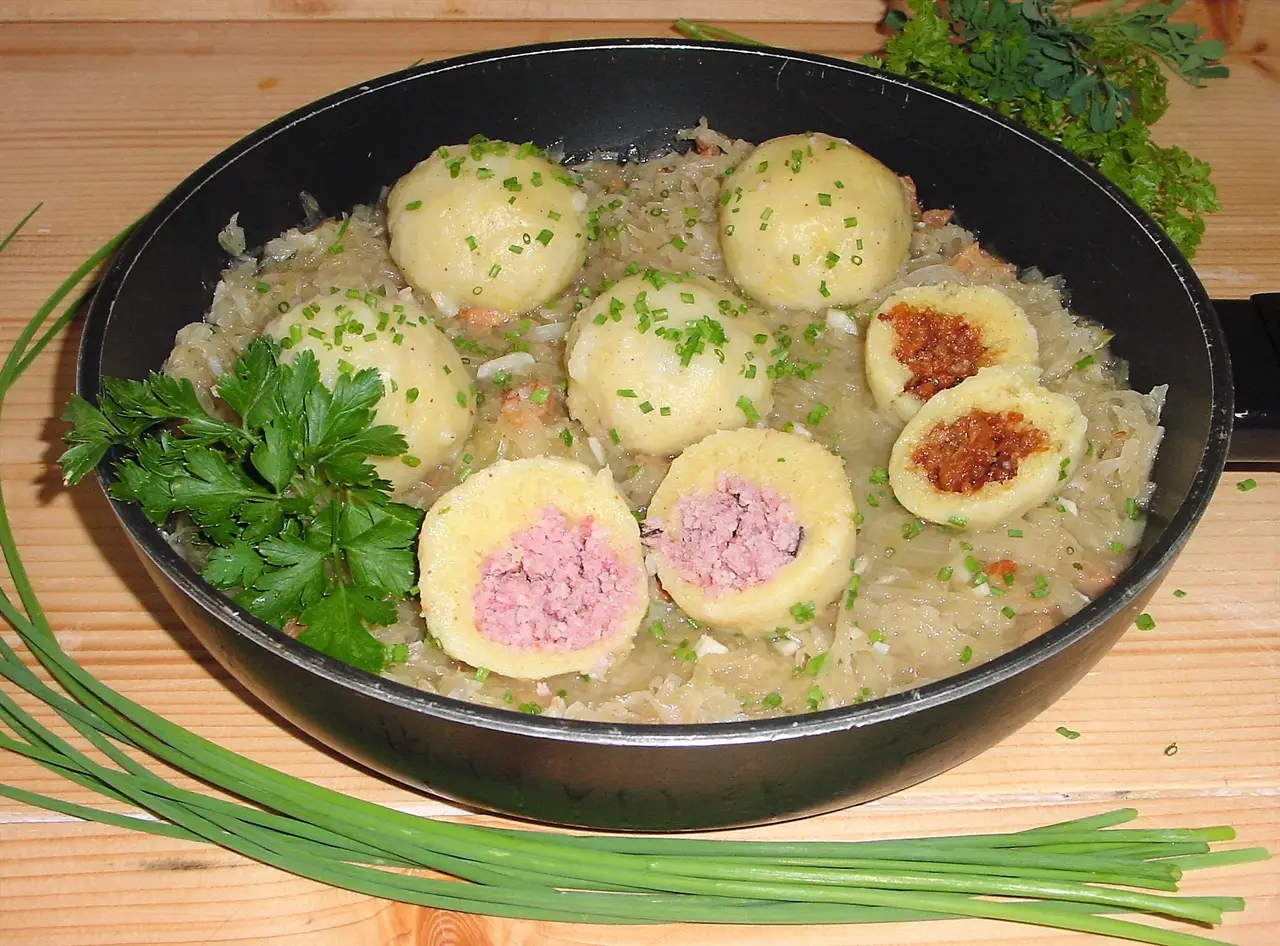 Erdäpf-Grammelknödel mit Sauerkraut mit Schnittlauch und Petersilie dekoriert